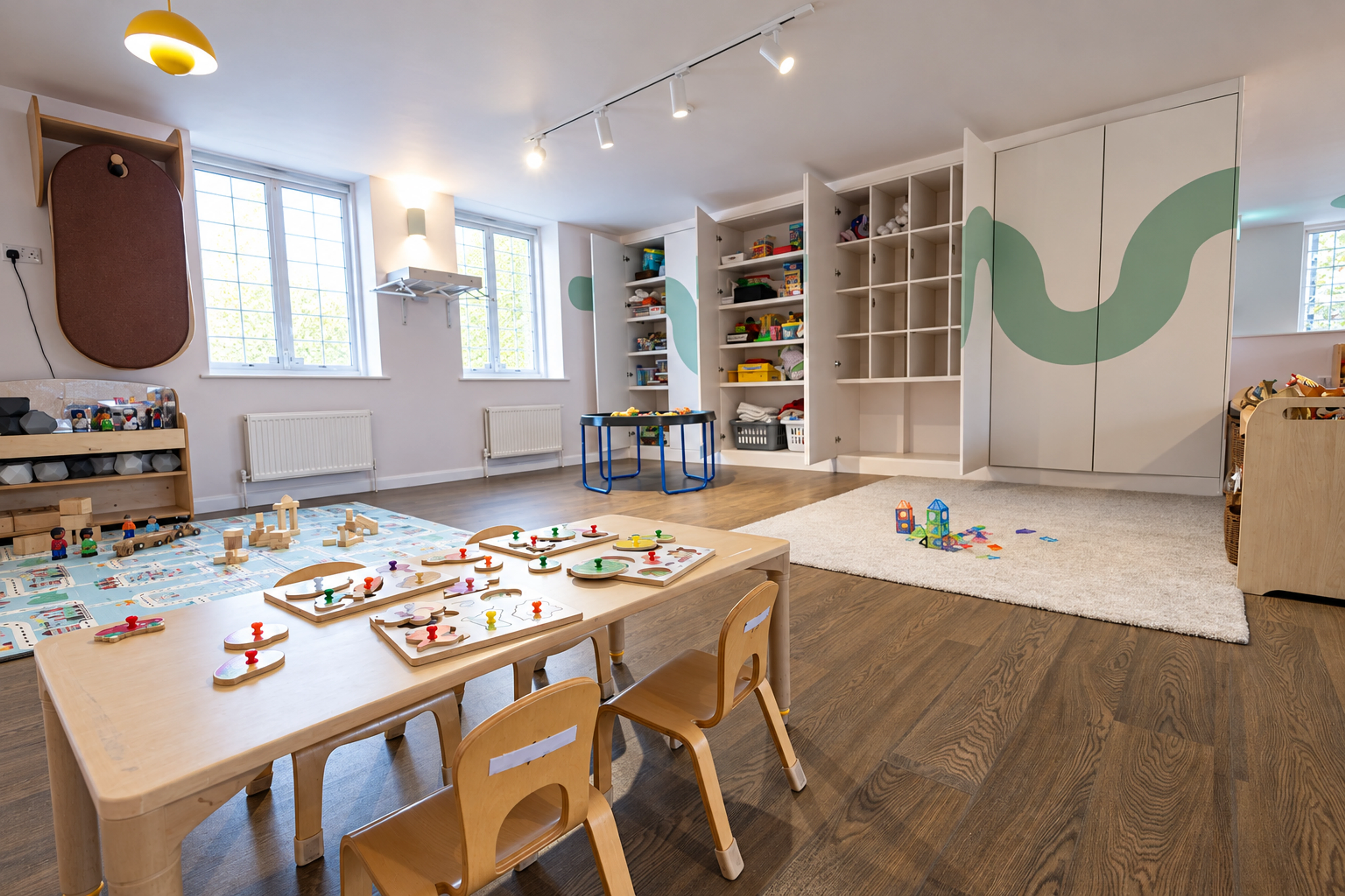 Bright Ealing nursery room with activity tables, fitted shelving and track lighting