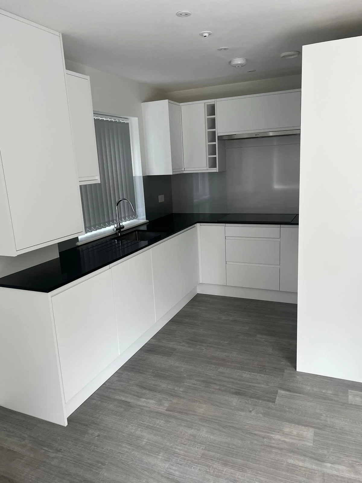 The completed kitchen with white cabinetry and dark worktops.