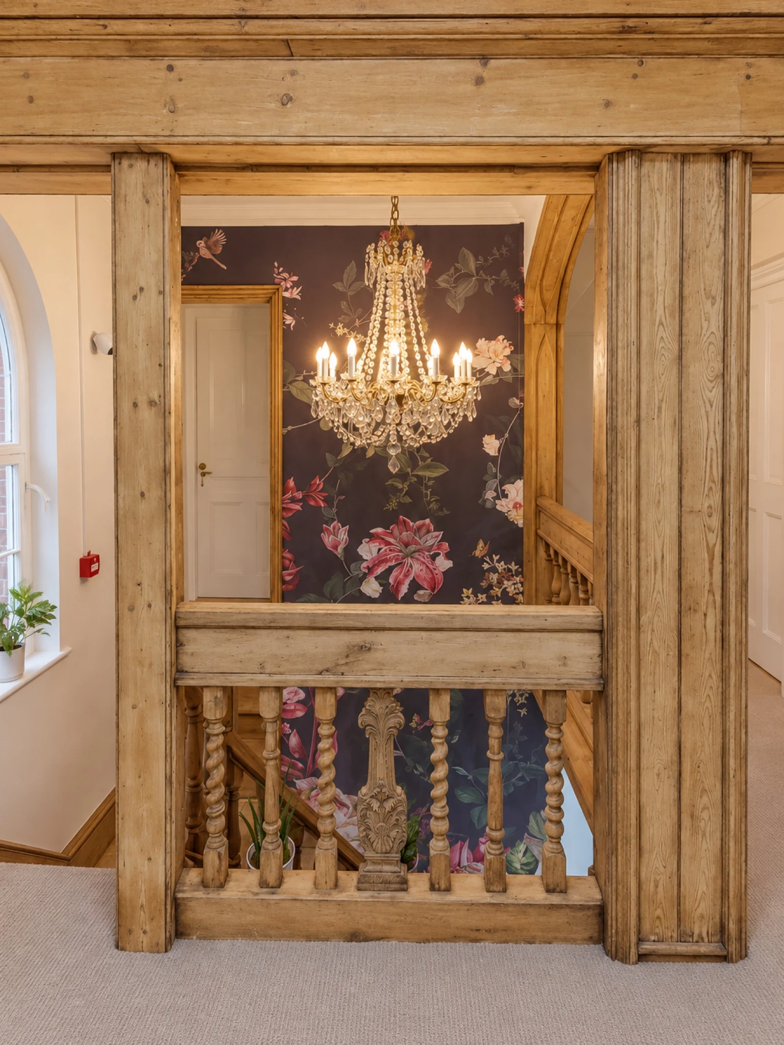 The timber-framed landing with a chandelier and floral wall finish.