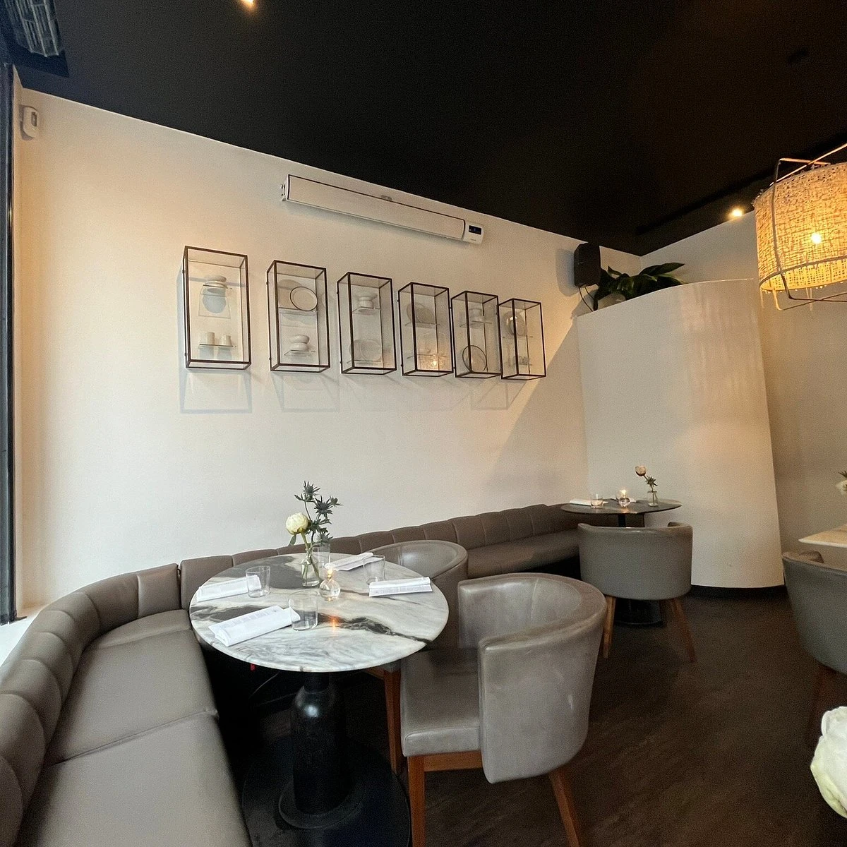 Curved upholstered banquette, marble table and framed artwork at Angelina Dalston